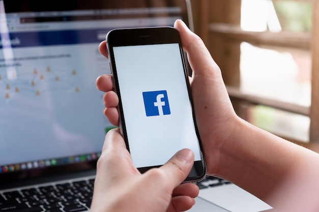 A women holds smartphone with Facebook In application on the screen