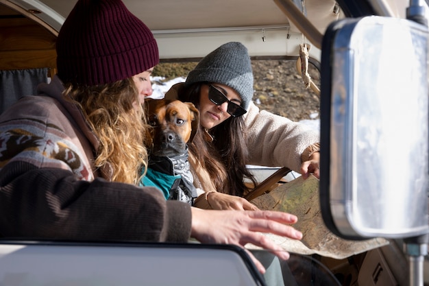 Women inside camper van consulting a map along with their dog