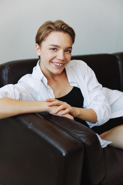 Women lying at home on the couch portrait with a short haircut in a white shirt smile depression in teenagers home holiday