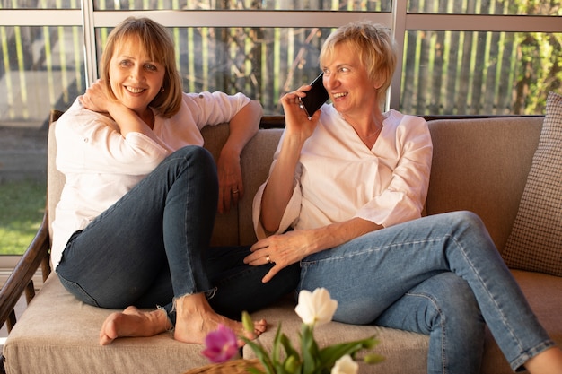 Women make online order in online store while sitting on veranda of wooden house using a smartphone