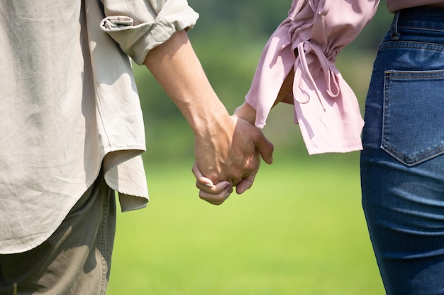 Women and men holding hands walking on the natural grass