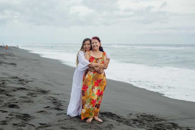 Women, mother and daughter enjoying quality time at the beach. Pacific Ocean, cloudy day.