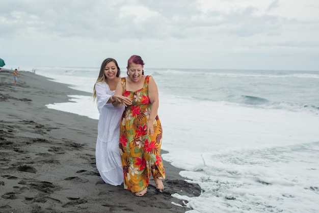 Women, mother and daughter enjoying quality time at the beach. Pacific Ocean, cloudy day.