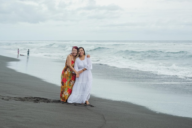 Women, mother and daughter enjoying quality time at the beach. Pacific Ocean, cloudy day.