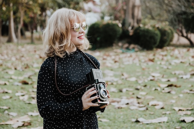 Women photography smilling,standing and hand holding retro camera in outdoor.Vintage tone