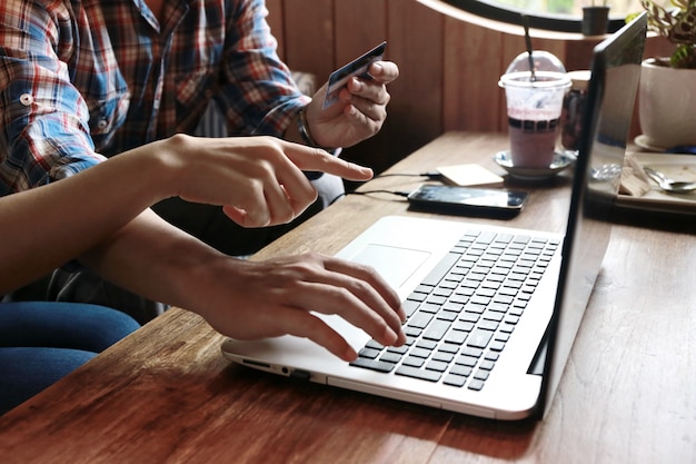 Women point to order man shopping online with credit card and laptop