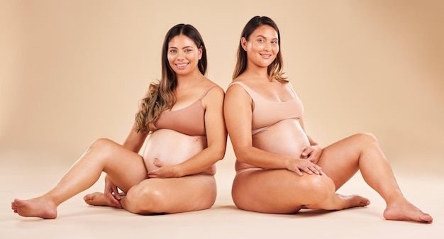 Women portrait or sitting and pregnancy stomach tummy growth progress or baby healthcare wellness on studio background Smile happy or friends in pregnant underwear for solidarity support or love