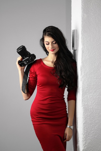 women in red dress keeping professional camera in her hands