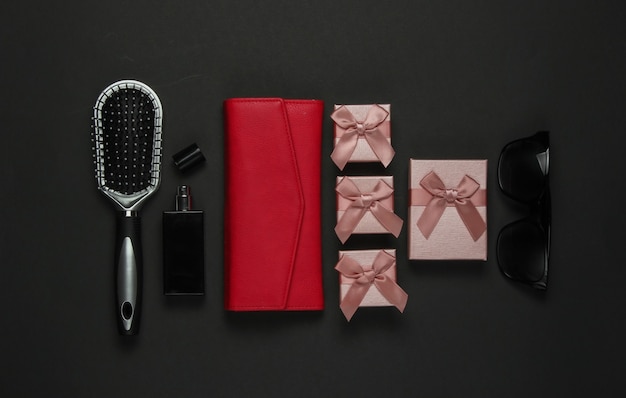 Women's accessories on a black background. Comb, sunglasses, perfume bottle, purse, gift box. Birthday, Mother's Day, Christmas. Top view