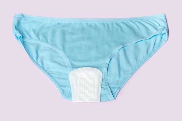 Photo women's blue underwear and white padding on a pink background top view flat lay concept minimalism women's health concept women's menstrual cycle