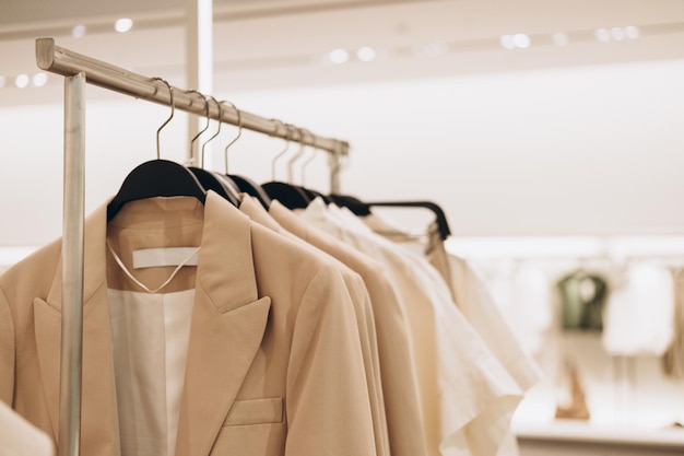 Women's clothes in beige colors on open hangers in store Selective focus copy space