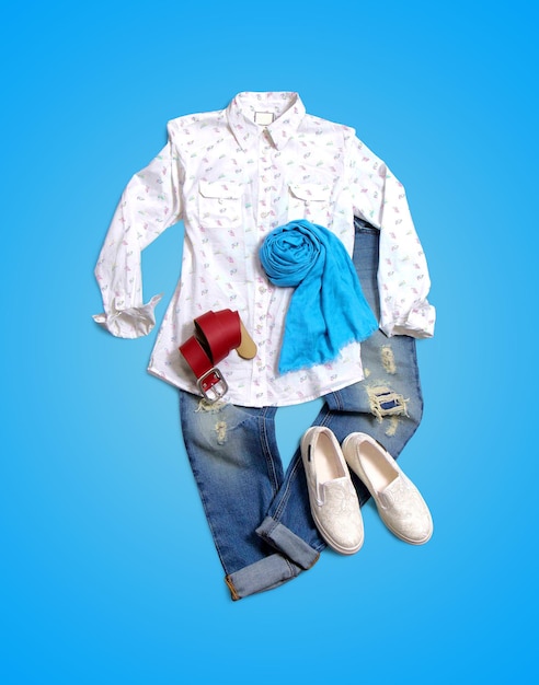 Women's clothing collection on blue background. Composition with blouse, belt, scarf and shoes