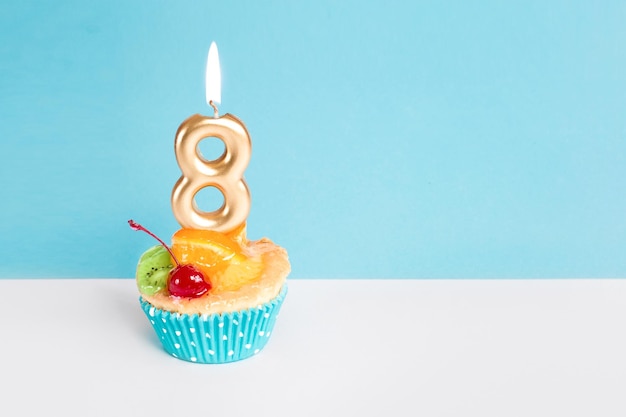 Women's Day 8 march Golden candle with number eight on a cake on a blue background