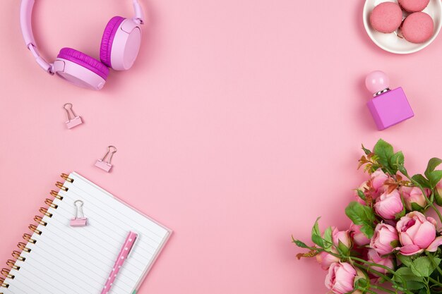 Women's or girls things, wireless headphones, roses, perfume, stationery on pink background