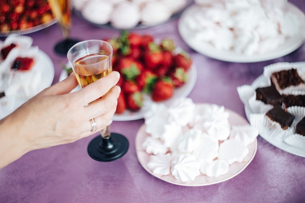 Women's hand holding a glass of champagne on the background of the festive table