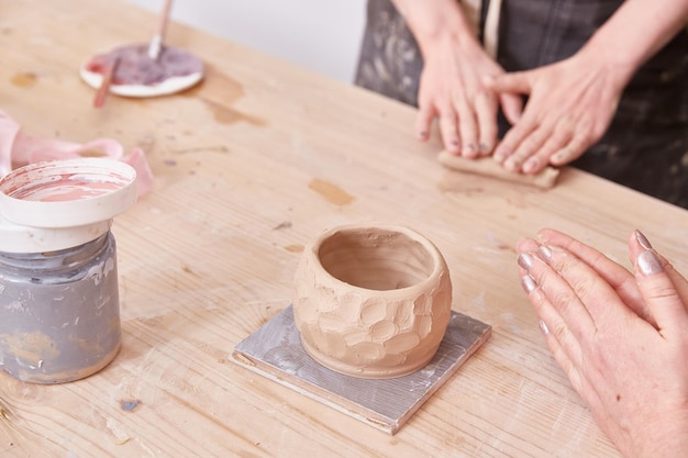 Women's hands are molded from clay The handle of a cup