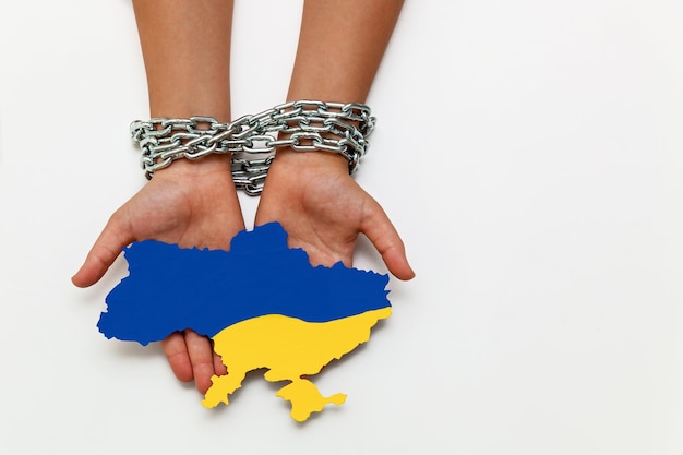 Women's hands are tied with a chain and holding a map of Ukraine painted in blue and yellow