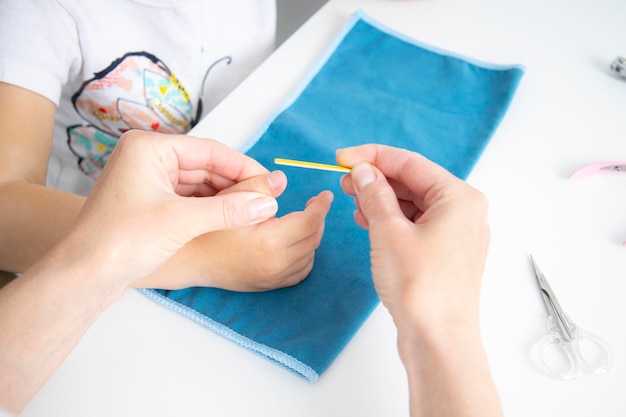 Women's hands on a child's hand file their nails with a nail file Top view flat lay