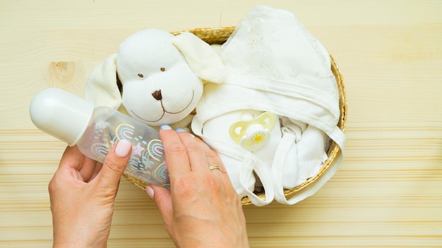 Women's hands collect items for a newborn in a basket