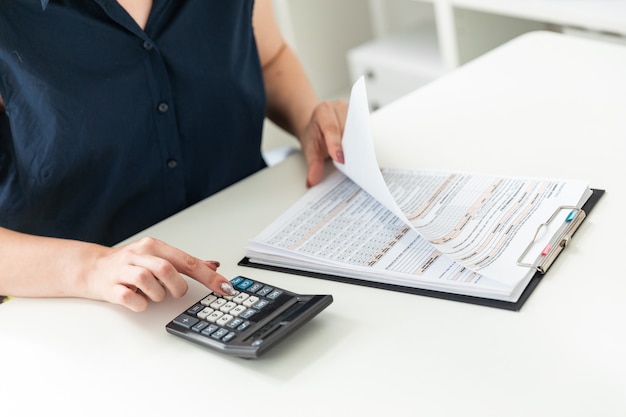 Women's hands count on the calculator and fill out the form.