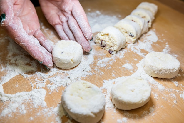 Women's hands in flour make a cheesecake shape from the dough to be prepared and fried in a pan