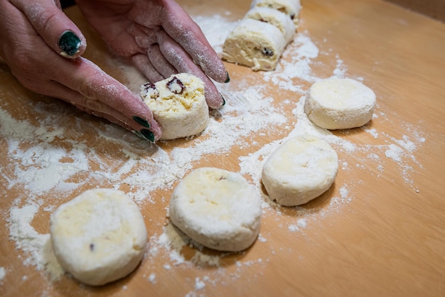 Women's hands in flour make a cheesecake shape from the dough to be prepared and fried in a pan