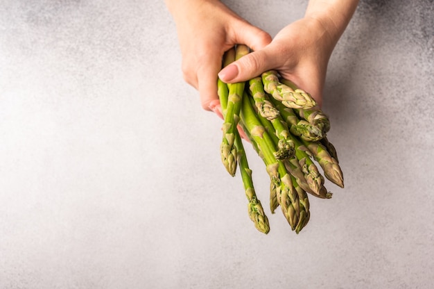 Women's hands hold a bunch of fresh green asparagus