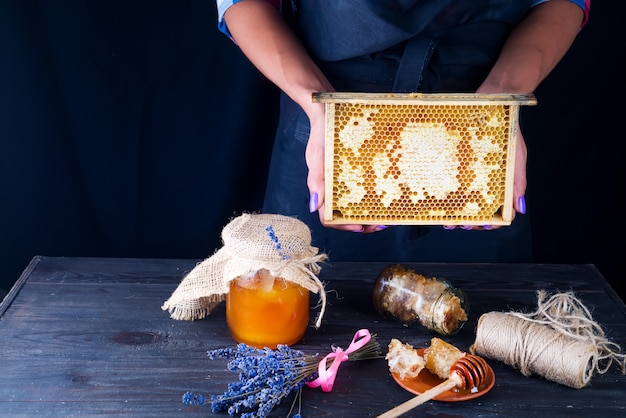 Photo women's hands hold honey combs with organic honey on a dark background