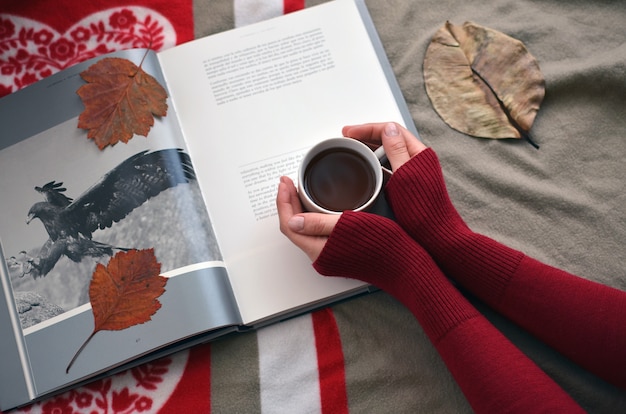 Women's hands holding a Cup of coffee on the book