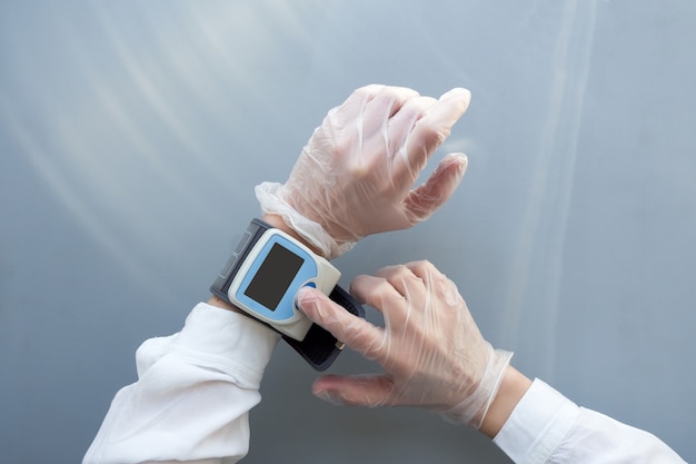 Women's hands in medical gloves use a blood pressure monitor. Healthcare medical doctor concept. Mock up.