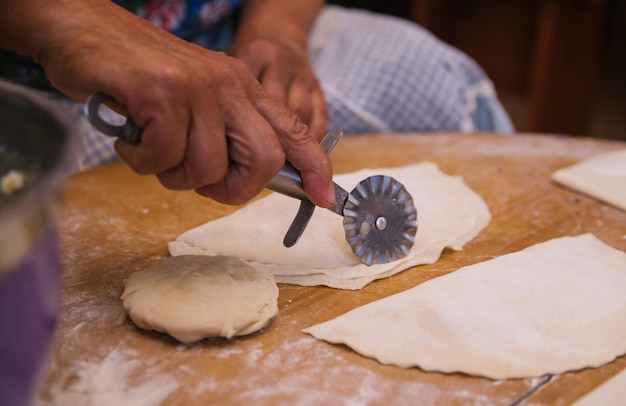 Women's hands in the process of cooking kutaba or chebureks minced meat and onions in the doughCottage cheese and onion in the dough Azerbaijani Tatar Caucasian Greek cuisine