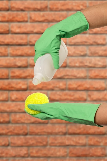 Women's hands in protective gloves with bottle of dishwashing liquid