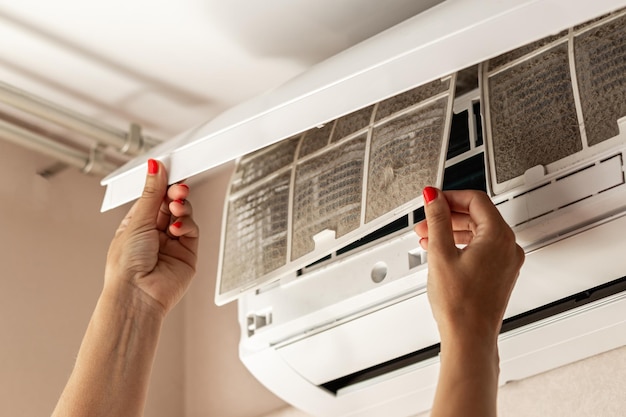 Women's hands take out dusty filters from the air conditioner