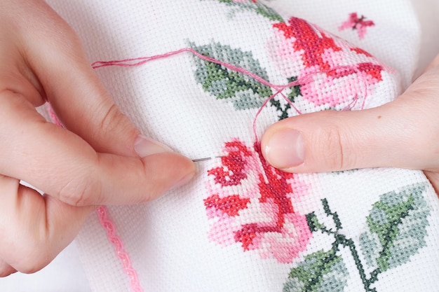 Photo women's hands with a cross embroidered on the fabric patterns of flowers roses