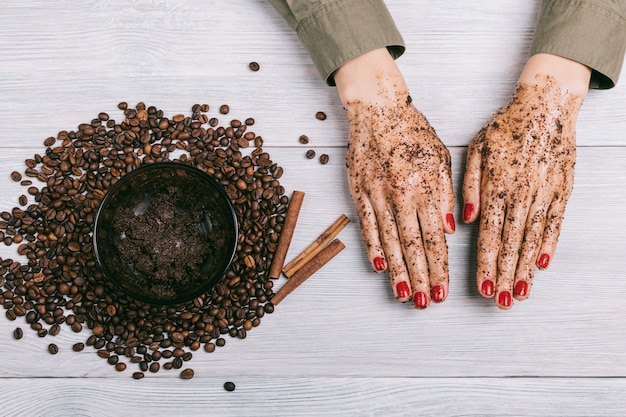 Women's hands with red nail polish in a coffee scrub