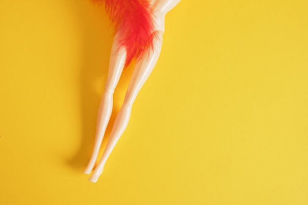 Women's health concept doll and red feather on yellow background