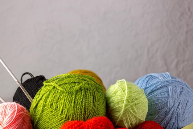 Women's hobby knitting.Yarn of bright colors on a gray background. Place for your text.