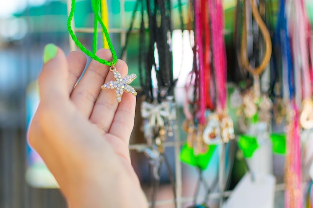 Women's imitation jewelrybeads necklaces on the showcase of street trading A woman's hand chooses beads