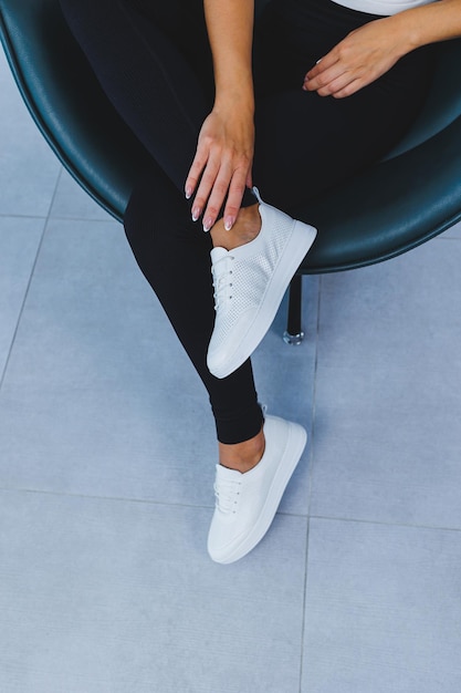 Women's legs closeup in white leather sneakers made from natural leatherCollection of women's summer shoes