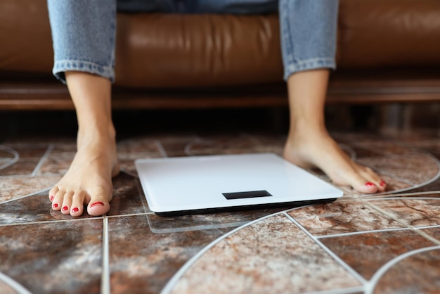 Women's legs and scales on the floor closeup