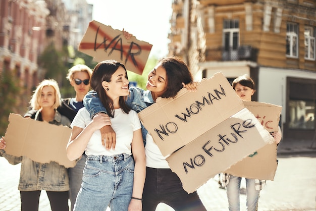 Women s rights are human rights two happy young women are holding signboards and smiling