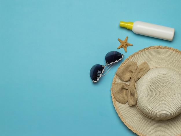 Photo women's sun hat with sunglasses and sunscreen. the concept of summer holidays and travel.