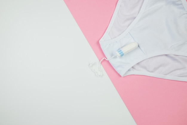 Women's white tampon panties on a pink and white background with copy space top view