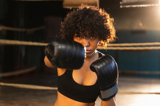 Women self defense power African american woman fighter punching with boxing gloves to camera Healthy strong girl punching training punches looking concentrated straight Fit body workout