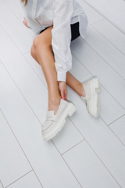 Women shoes Close up of female legs in leather white loafers New springsummer collection of women's leather shoes