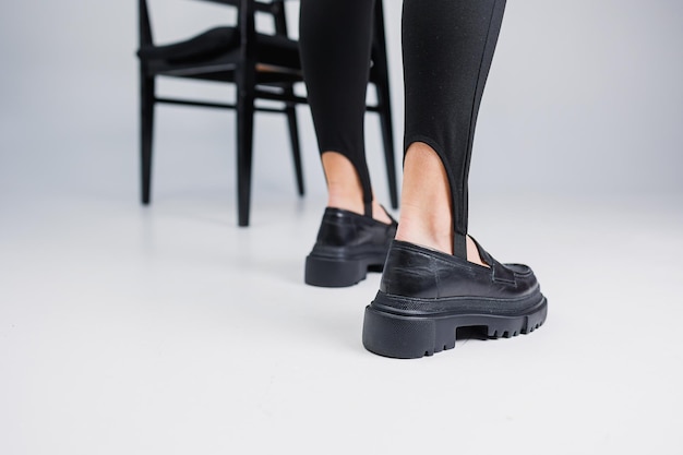 Women shoes Closeup of female legs in black leggings and black leather loafers New springsummer collection of women's leather shoes