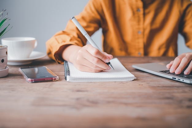 Women sitting and taking notes While working at home . Online communication