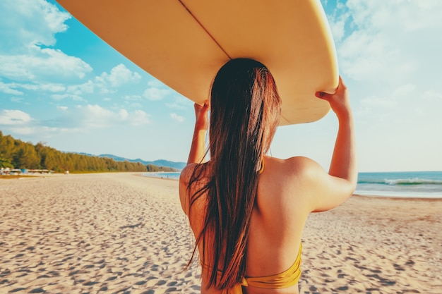 Women surfer with surfboard on beach