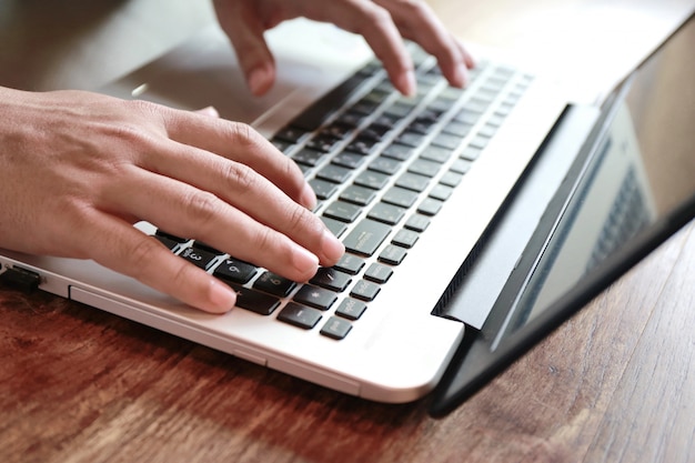 Women touching screen and man typing laptop on wood table