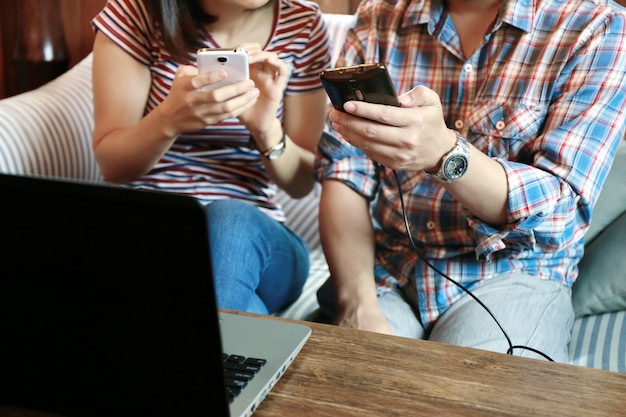 Women touching screen and man typing laptop on wood table